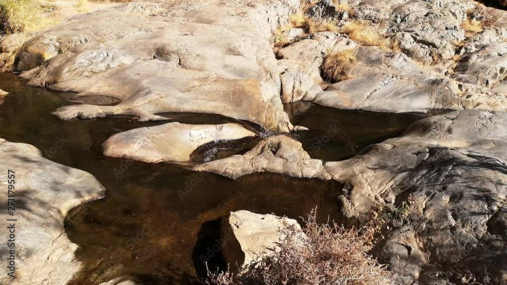Water flowing out of small pond over rocks in desert area. Water flowing out of small pond over rocks in desert area.