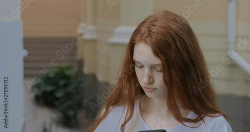 Girl paints lips using smartphone as a mirror. in slow motion. Shot on Canon 1DX mark2 4K camera photo