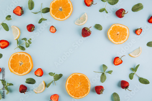 Fototapeta Naklejka Na Ścianę i Meble -  Summer colorful flat lay. Pattern made of citrus fruits, leaves and strawberries on the blue wooden table. Top view and copy space