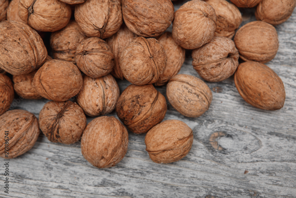 a scattering of walnuts on a wooden background close-up a scattering of walnuts on a wooden background close-up