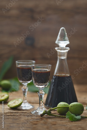 Bottle and two glasses with walnut liquor. Homemade wallnut liquer full od iodine and vitamins. Vertical image.
