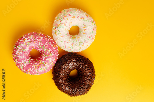 pink white and black chocolate donuts on yellow background top view