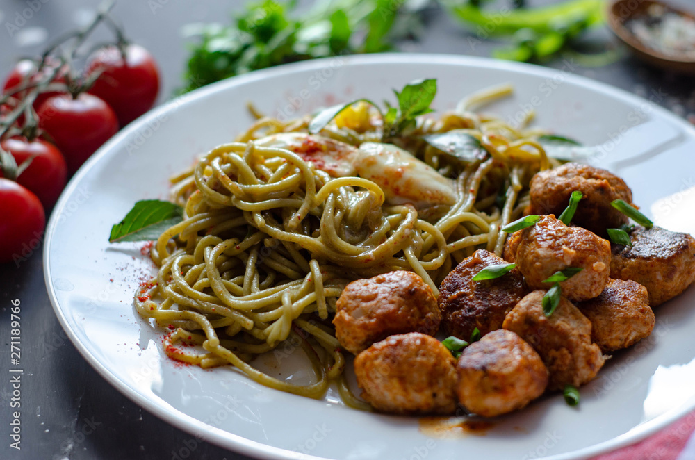 Spinach spaghetti with meatballs and egg. Green tasty pasta served with cherry tomatoes and basil Spinach spaghetti with meatballs and egg. Green tasty pasta served with cherry tomatoes and basil
