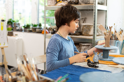 Φωτογραφία Dark-haired talented boy sculpting figures with clay