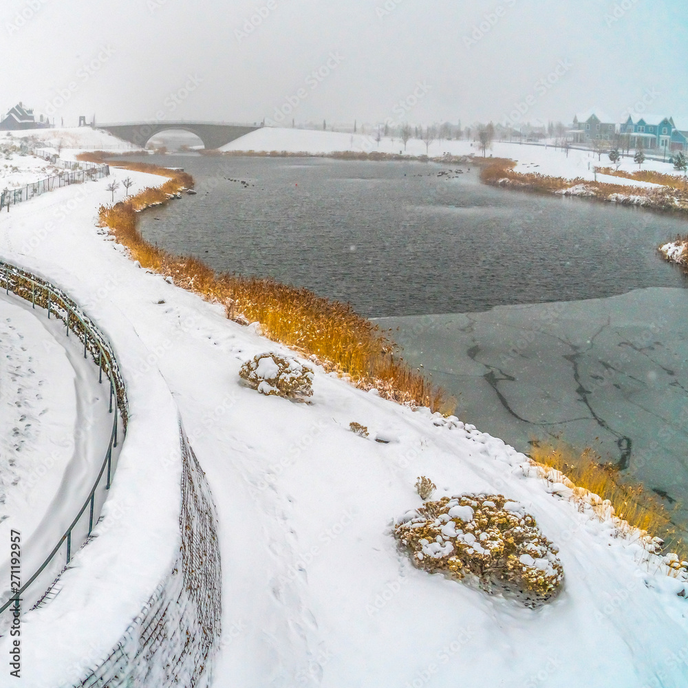 Square frame Spiralling path going up a bridge near an icy lake in Daybreak Utah