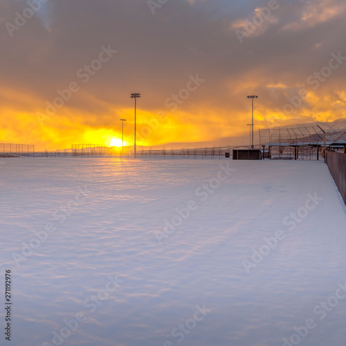 Square Stunning winter scenery with a golden sun setting against the sky filled clouds