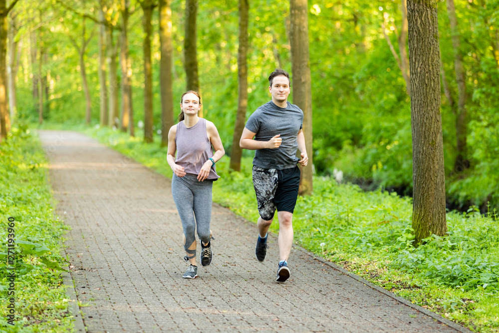 Fototapeta premium young woman and man running in a forest and making fitness