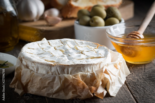 Camembert and brie cheese on wooden background with tomatoes, letuce and garlic. Italian food. Dairy products.