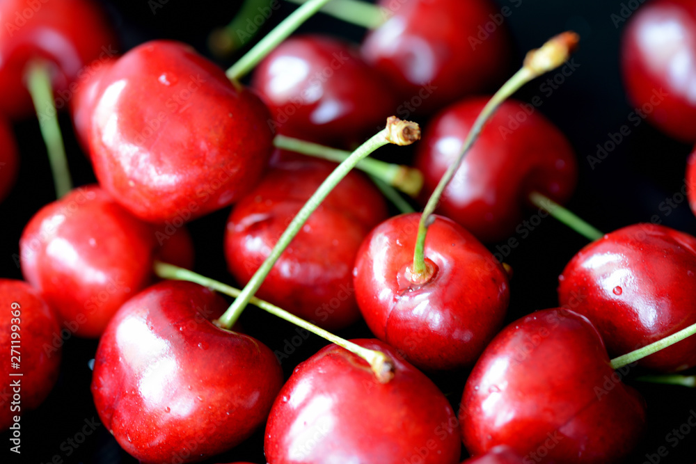 Ripe sweet cherry berries with water drops on a dark background close up Ripe sweet cherry berries with water drops on a dark background close up