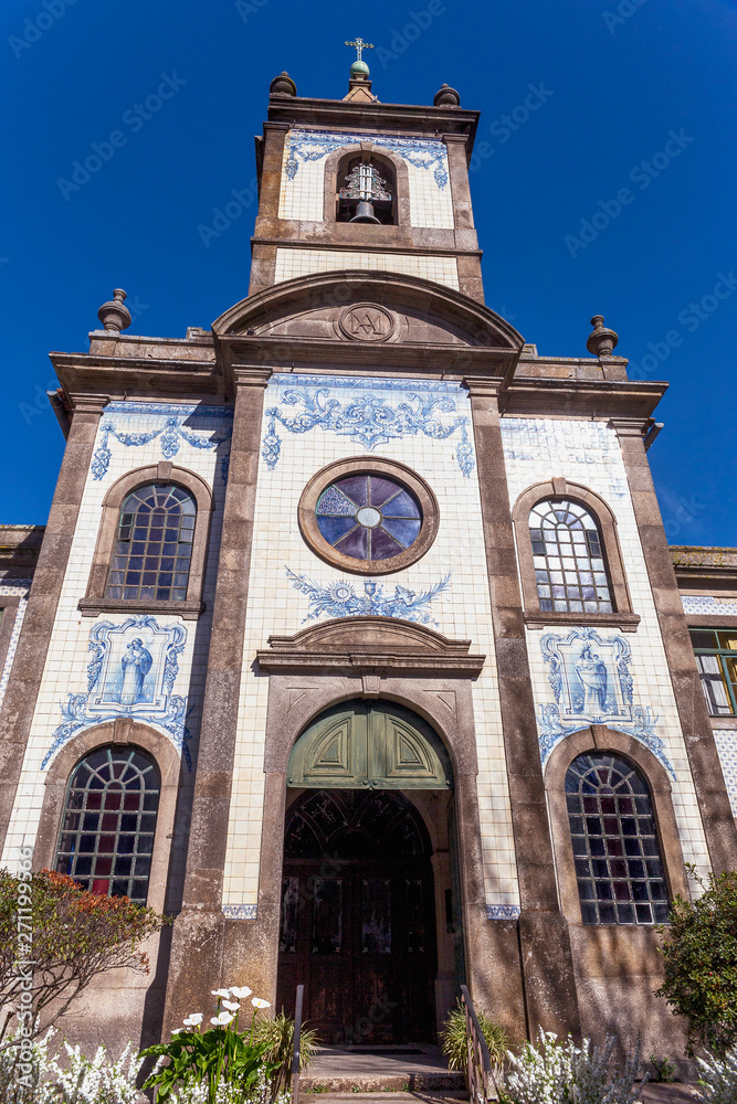 front view of the entrance to a small cathedral with a azulezhu facade in the Portuguese city of Porto