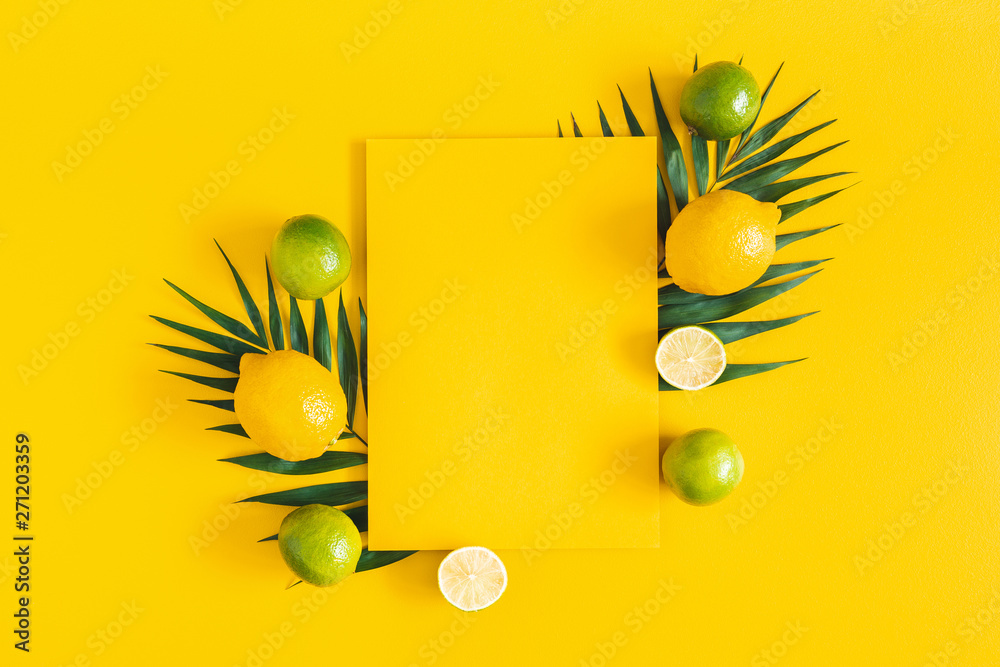 Fototapeta Letnia kompozycja. Tropikalne liście palmowe, owoce cytrusowe, żółty papier pusty na żółtym tle. Koncepcja lato. Płaski układanie, widok z góry, kopia przestrzeń