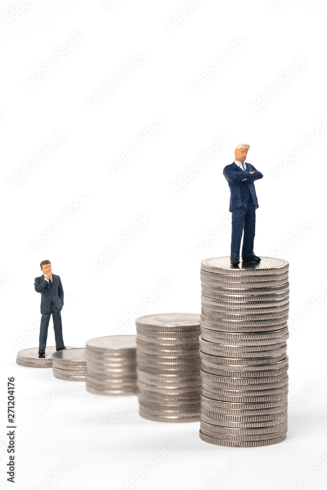 two miniature businessmen standing on coin stacks two miniature businessmen standing on coin stacks