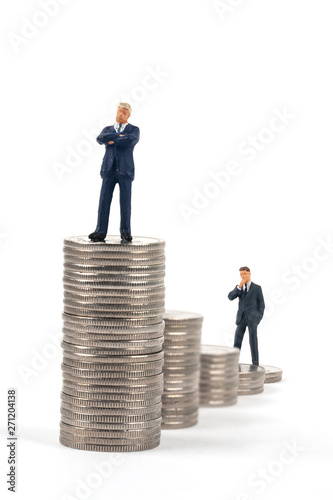 two miniature businessmen standing on coin stacks 