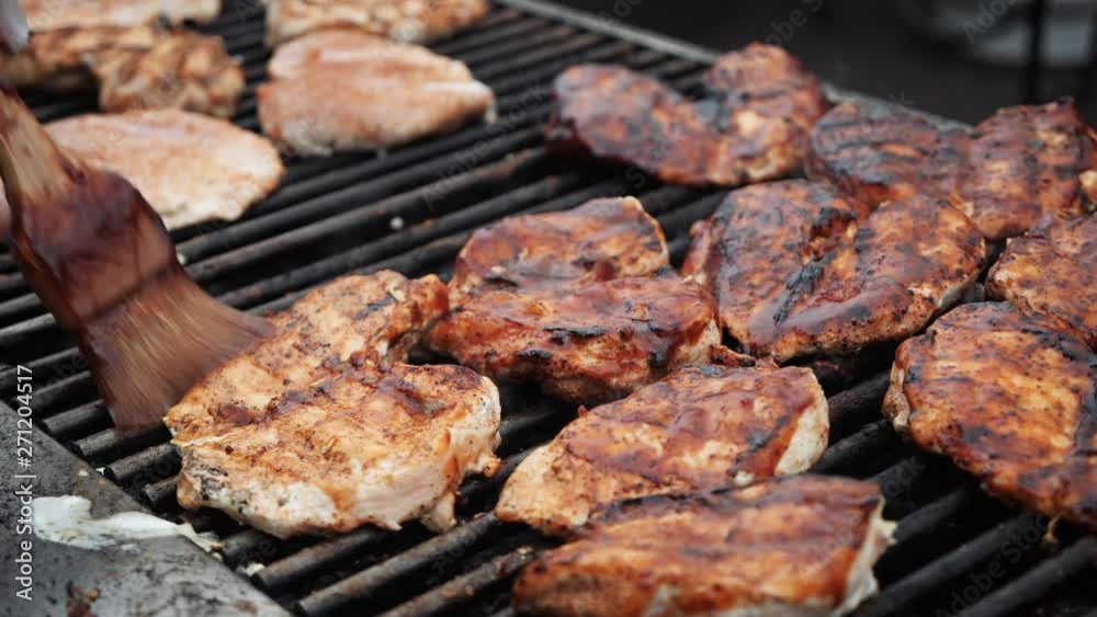 Brushing some juicy barbeque grilled chicken with bbq sauce at an outdoor catering event. Slow motion. Brushing some juicy barbeque grilled chicken with bbq sauce at an outdoor catering event. Slow motion.