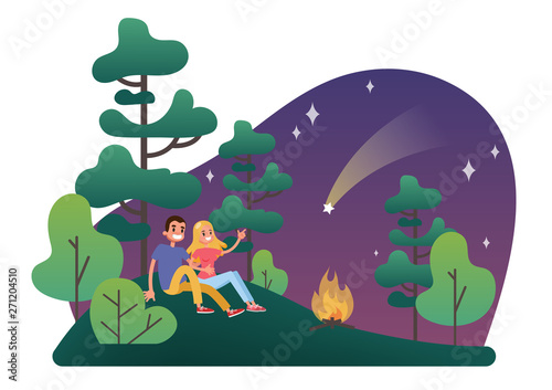 Man and woman sitting on the grass at the campfire