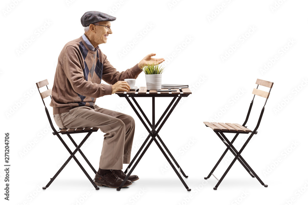 Senior man sitting at a table drinking coffee and gesturing a conversation
