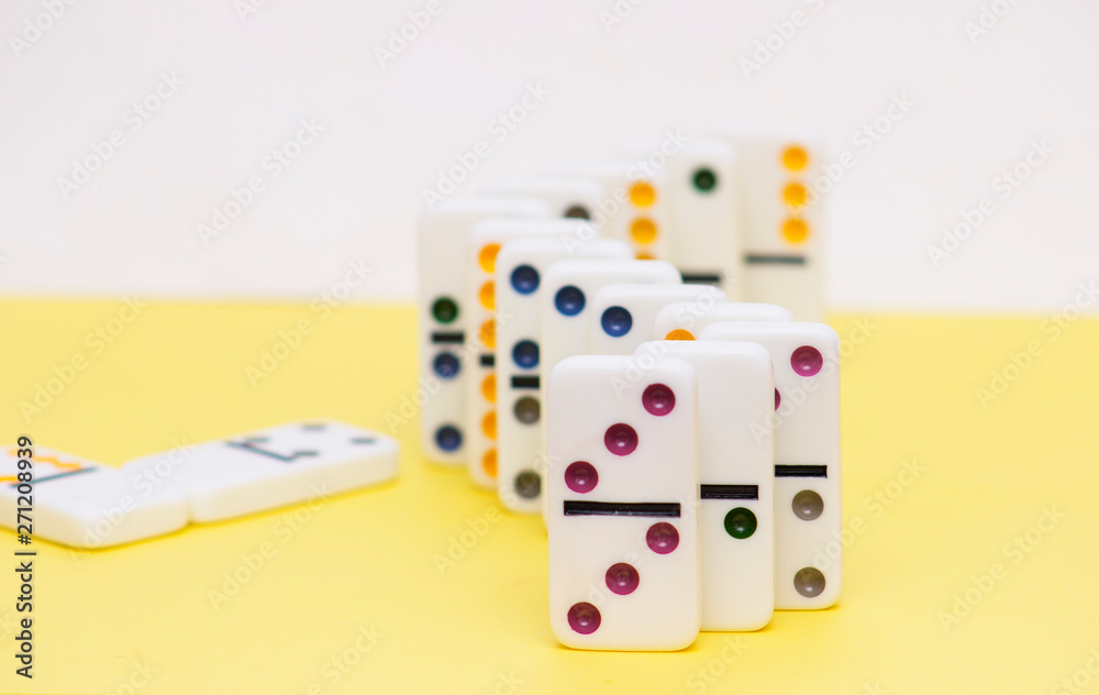 Domino game pieces standing in a row on yellow background Domino game pieces standing in a row on yellow background