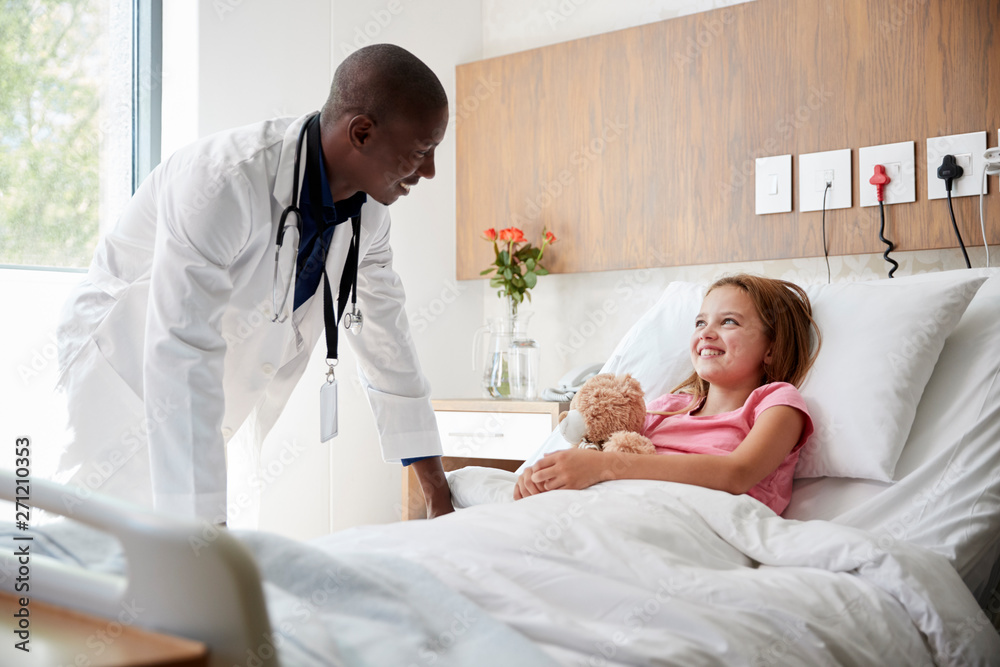 Male Doctor Visiting Girl Lying In Hospital Bed Hugging Teddy Bear Male Doctor Visiting Girl Lying In Hospital Bed Hugging Teddy Bear