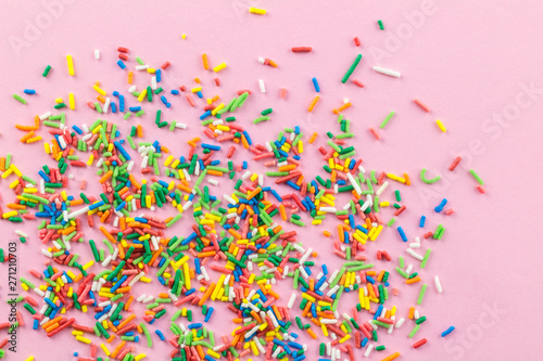 Sprinkles on pink background - Many multi-colored sprinkles on pink - top view