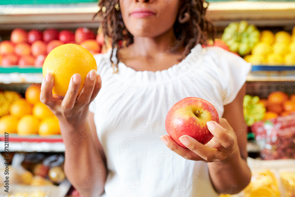 Young woman choosing between apple and orange when shopping at supermarket Young woman choosing between apple and orange when shopping at supermarket