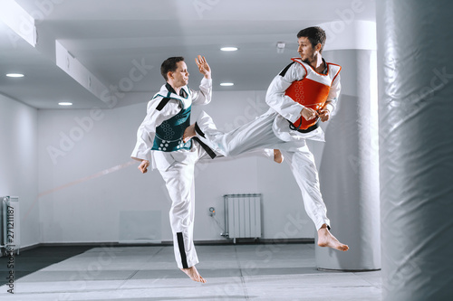 Photos Two Caucasian sporty men sparring in tekwondo fittings barefoot.