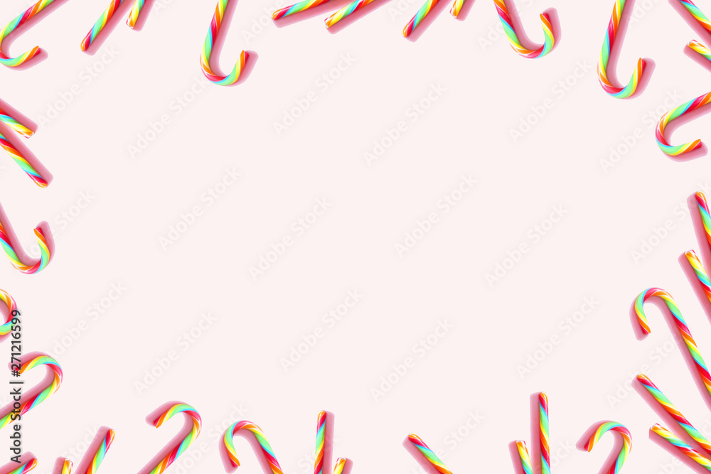 Multicolored candy canes on pastel pink background. Holiday frame of sweets for celebration, carnival, party, festive, sales. Copy space. Multicolored candy canes on pastel pink background. Holiday frame of sweets for celebration, carnival, party, festive, sales. Copy space.