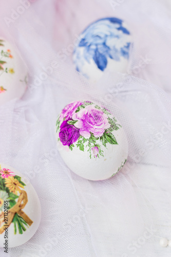 Decorated Easter eggs and flowers on white tulle background; decoupage technique