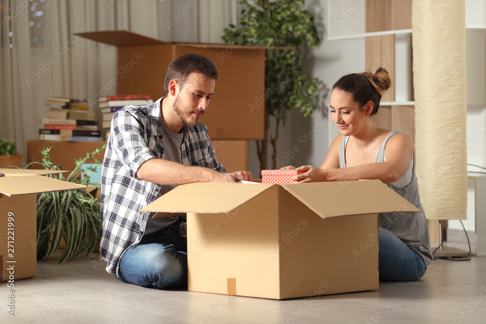 Serious couple boxing belongings on the floor moving house Serious couple boxing belongings on the floor moving house