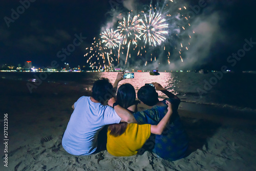 Fotografija group of friends sitting and holding each others enjoy watching fireworks displa