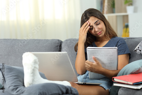 Worried disabled student studying on a couch at home