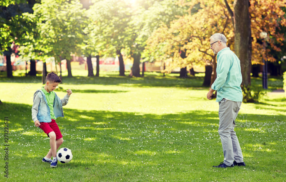 Obraz premium family, generation, game, sport and people concept - happy grandfather and grandson playing football at summer park