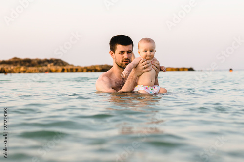 Father and baby swim in the sea in Cyprus. Dad teaches daughter how to swim