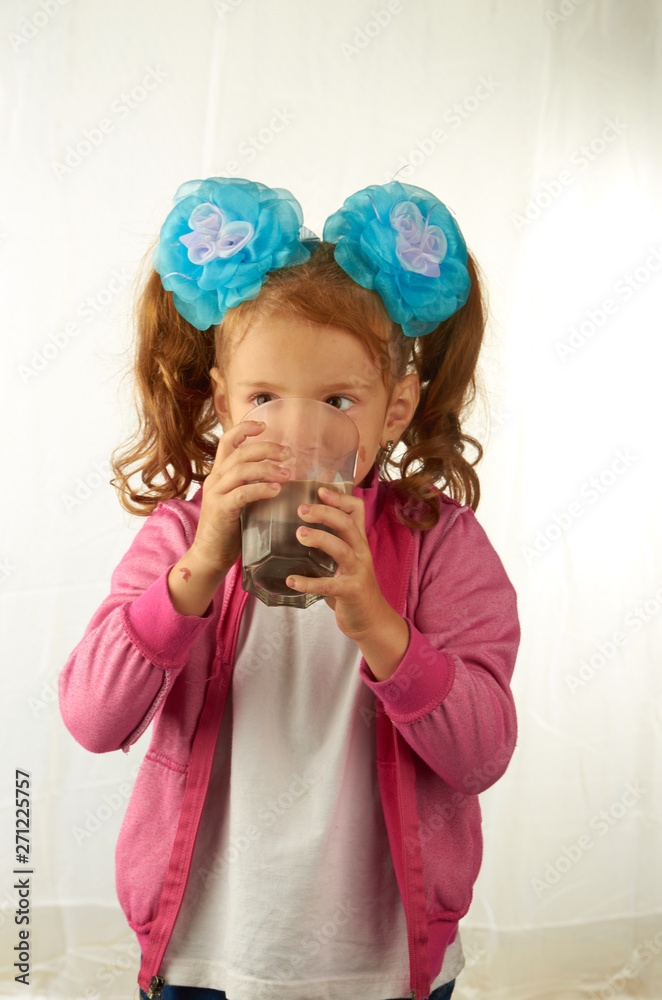 Girl with bows drinking cocoa from a large transparent glass Girl with bows drinking cocoa from a large transparent glass
