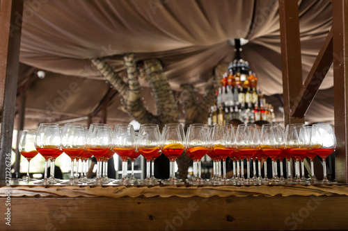 A lot of cocktails at the bar at the wedding party. Glasses with apperol and with a slice of lemon close-up photo