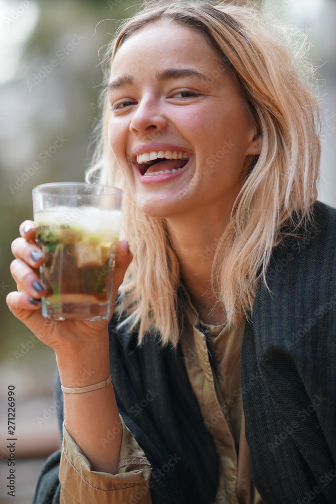 Cheerful young woman holding a cocktail grass outdoors Cheerful young woman holding a cocktail grass outdoors