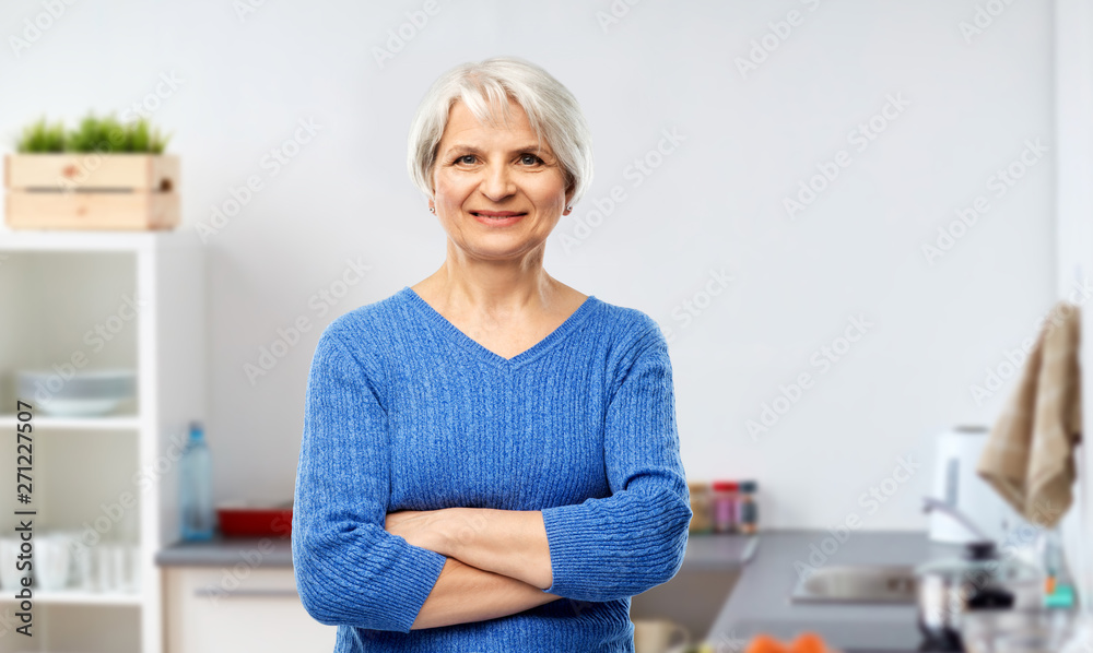 cooking and old people concept - portrait of confident smiling senior woman in blue sweater with crossed arms over kitchen background cooking and old people concept - portrait of confident smiling senior woman in blue sweater with crossed arms over kitchen background