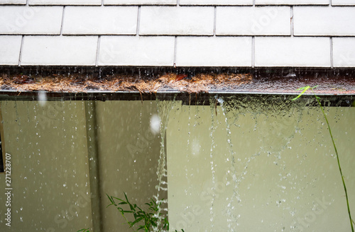 Close up on section of rain gutter clogged with leaves, debris on residential home during the rain photo