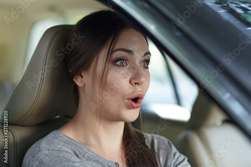 Foto Young attractive caucasian woman behind the wheel driving a car with grimace of astonishment or shock, mouth opened