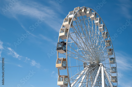 Ferris wheel on blue sky with white clouds background. © Alex Puhovoy