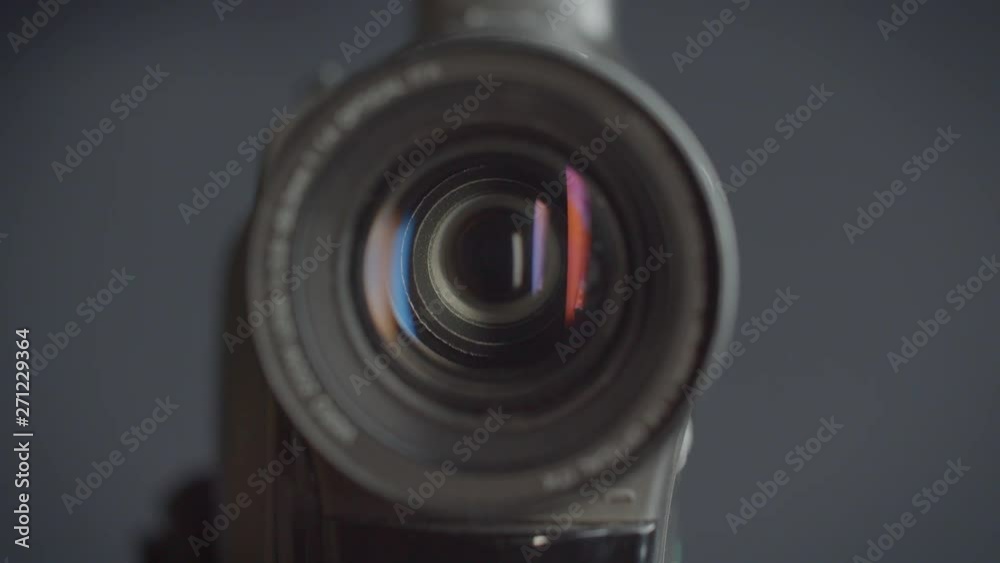 Close-up shot of the objective of videocamera with red reflections in it.