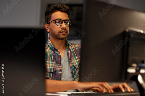 deadline, technology and people concept - close up of creative man in glasses working at night office and thinking photo