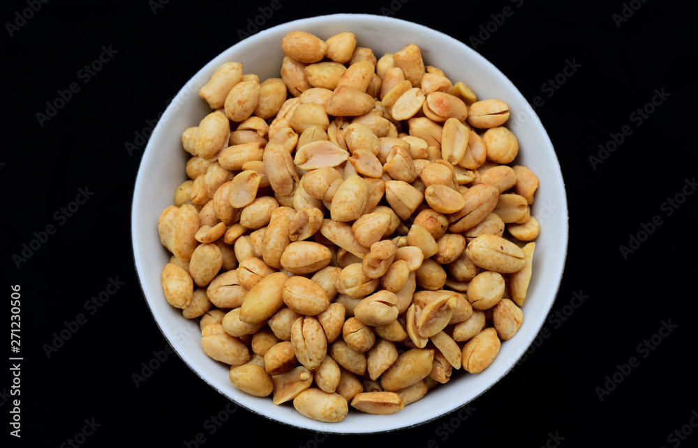 Salted fried peanuts on a plate with a blank black background. Salted fried peanuts on a plate with a blank black background.