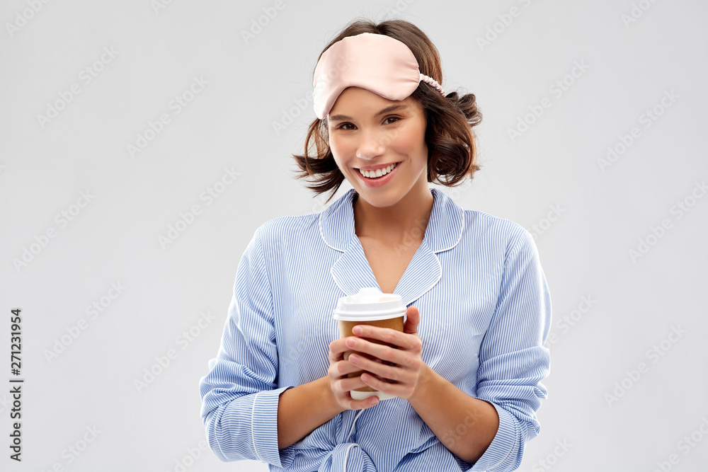 people and bedtime concept - happy young woman in pajama and eye sleeping mask with takeaway paper cup of coffee over grey background people and bedtime concept - happy young woman in pajama and eye sleeping mask with takeaway paper cup of coffee over grey background