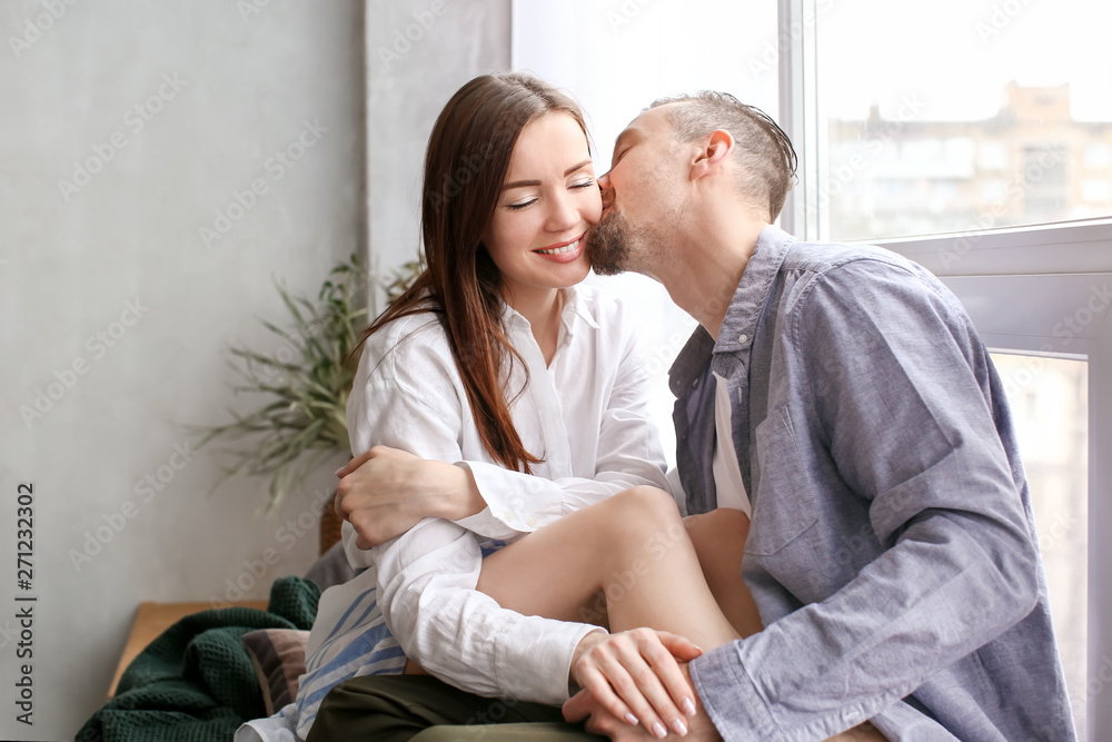 Happy couple resting near window at home Happy couple resting near window at home