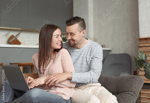 Happy couple with laptop at...