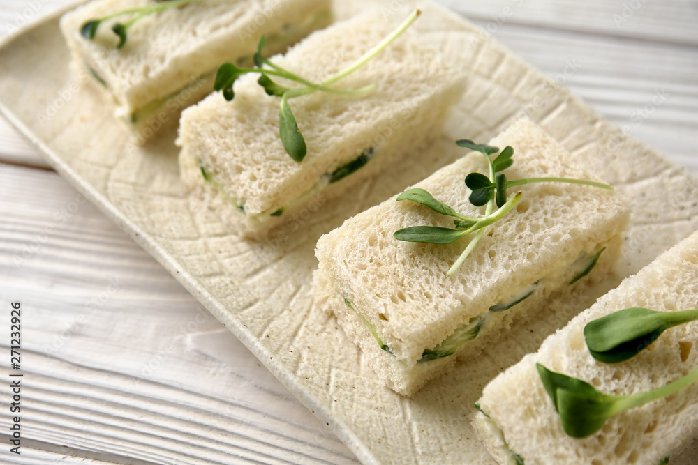 Plate with tasty cucumber sandwiches on white table