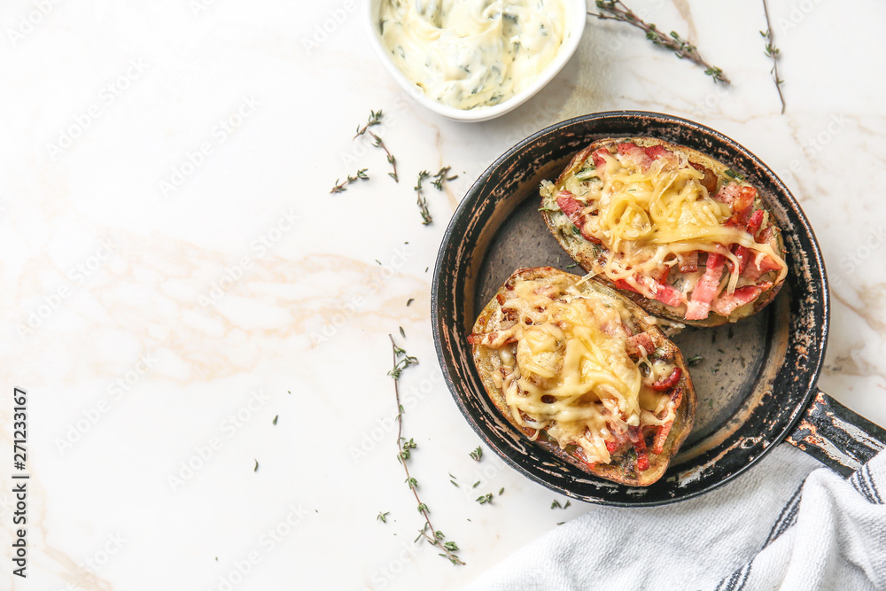 Frying pan with tasty stuffed potato and sauce on light table