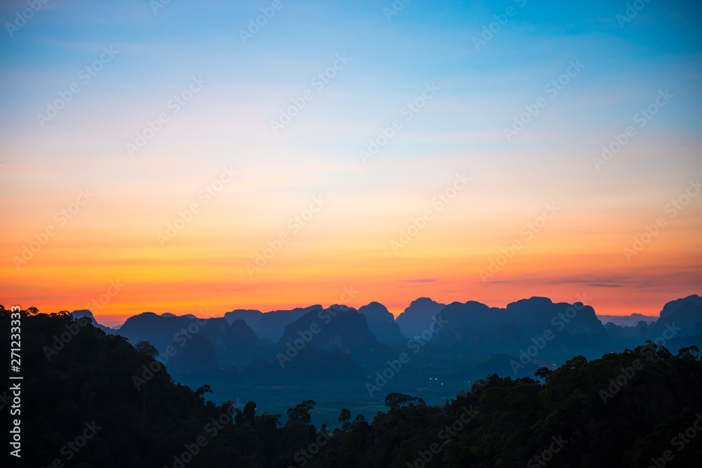 Landscape with beautiful dramatic sunset and silhouette of blue mountains at horizon, Thailand
