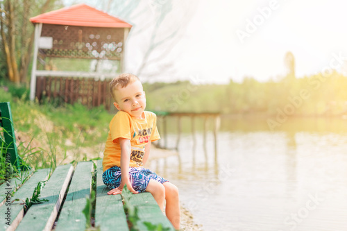 The boy sits on the lake in the summer
