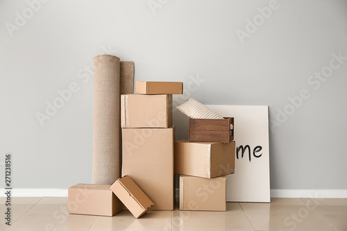Cardboard boxes with belongings prepared for moving into new house near light wall
